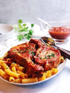 a white plate topped with pasta and meat covered in sauce