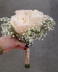 a person holding a bouquet of white roses in their hand with pearls on the wrist