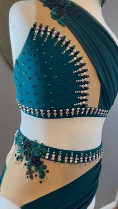 a woman wearing a green and white belly wrap with beading on the bottom, in front of a mannequin