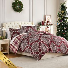 a bed with a red and white comforter next to a christmas tree