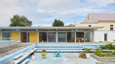 an empty swimming pool in front of a house with yellow and blue paint on the walls