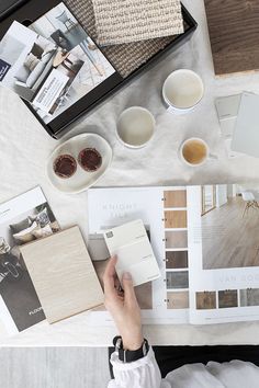 a person sitting at a table with some paint samples and other things on the table