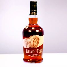 a bottle of buffalo trace whiskey sitting on a table with a white wall in the background