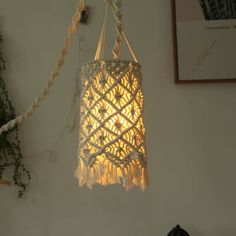 a light hanging from the side of a wall next to a potted plant on a table