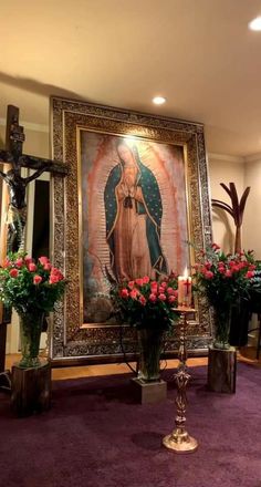 the altar has flowers and candles in front of an immaculate virgin mary painting on the wall