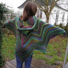 a woman standing on a deck wearing a multicolored shawl