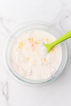 a glass bowl filled with milk and a green spoon