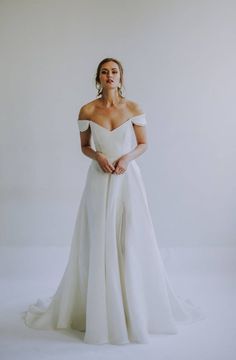 a woman in a white wedding dress posing for the camera with her hands on her hips