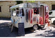 an ice cream truck parked in front of a building with clothes hanging out to dry