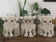 three mason jars decorated with white crocheted doily and eyeglasses are sitting on a wooden table