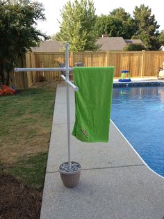 a green towel hanging on a pole next to a pool