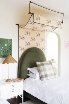 a bed with white sheets and green headboard