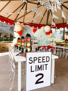 a speed limit sign sitting on top of a white table under a large tent covered in balloons