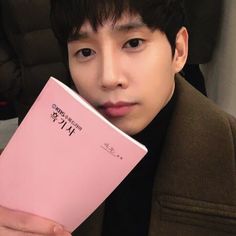 a man holding up a pink book in front of his face