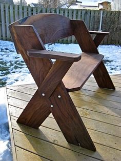 a wooden chair sitting on top of a deck in the middle of snow covered ground