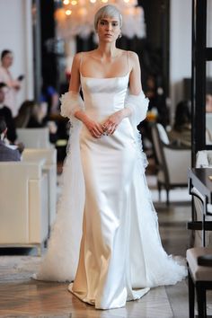 a woman in a white wedding dress walking down the aisle with her hand on her hip