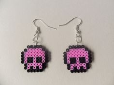 a pair of pink and black pixelated earrings with silver hooks on a white surface