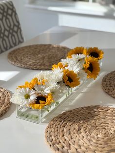 sunflowers and daisies are arranged in a vase on a white countertop