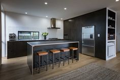 a modern kitchen with stainless steel appliances and bar stools