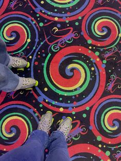 two people standing on a colorful rug with swirls