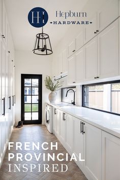 a kitchen with white cabinets and wood flooring next to a black door that leads to a large window