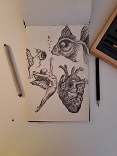 a pencil drawing of two heart shaped fish and a human body on paper next to a pen