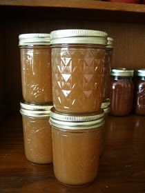 four jars filled with peanut butter sitting on top of a wooden table next to apples