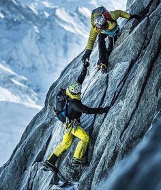 two climbers are climbing up the side of a mountain in yellow and black gear