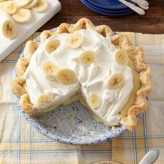 a banana cream pie on a blue and white plate next to some plates with silverware