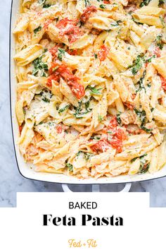 baked fettuccine with tomatoes and spinach in a white casserole dish