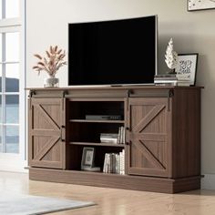 a flat screen tv sitting on top of a wooden entertainment center next to a window