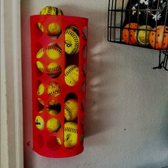 a red rack filled with yellow baseballs next to a wall mounted birdcage