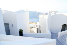 an aerial view of a white building with blue doors and windows, overlooking the ocean