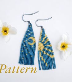 two pairs of beaded earrings with yellow and blue designs on them next to white flowers