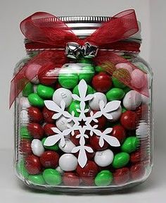 a glass jar filled with candy and candies covered in snowflakes, christmas decorations, and bows