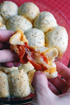 someone is holding a piece of pizza in front of some balls of food on a plate