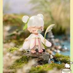 a small figurine is sitting on a mossy rock