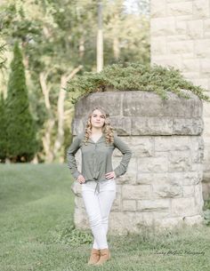 a woman standing in front of a stone wall with her hands on her hips and looking up