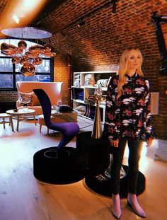 a woman is standing in the middle of a room with chairs, tables and lamps