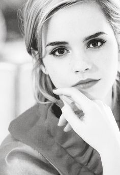 a black and white photo of a woman with her hand on her chin looking at the camera