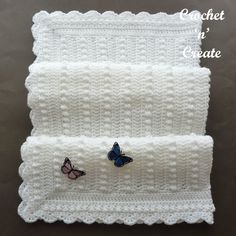 two white crocheted placemats with butterfly pins on them, one in the shape of a rectangle