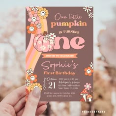 a person holding up a birthday card with flowers and pumpkins on it, in front of some trees