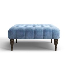 an upholstered bench with wooden legs and a blue velvet cover on the top