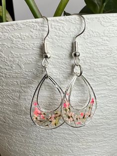 Dainty little resin and pressed flower earrings set in a silver colored metal bezel. Hang about 1 1/2" long. Teeny tiny flowers in shades of pink. Handmade Pink Teardrop Flower Earrings, Pink Teardrop Flower Earrings With Ear Wire, Silver Pressed Flower Earrings, Pink Flower Earrings With Pressed Flowers, Pink Flower-shaped Earrings With Pressed Flowers, Silver Pressed Flowers Drop Earrings, Nickel-free Round Pink Flower Earrings, Silver Drop Earrings With Pressed Flowers, Round Pink Nickel-free Flower Earrings