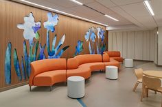 an office lobby with orange couches and paintings on the wall