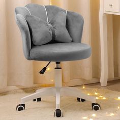 a gray office chair sitting on top of a white desk next to a window with lights