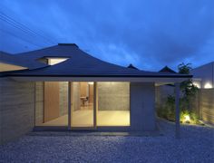 a house that is sitting in the middle of a gravel field at night with its lights on