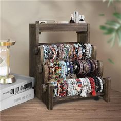 a stack of bracelets sitting on top of a wooden stand next to a book