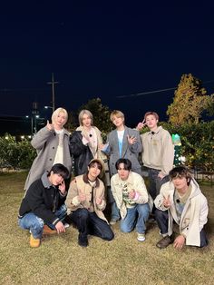 a group of young men posing for a photo in front of an apple tree at night