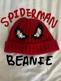 a red knitted beanie with eyes and the words spiderman beanie on it